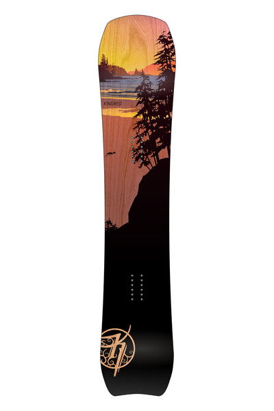 Kindred Tsitika snowboard. Topsheet artwork shows a colourful Vancouver Island sunset with dark conifers in the foreground. Woodgrain is visible through the transparent colours.